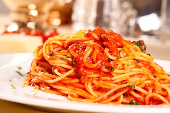 Plate of spaghetti topped with rich marinara sauce and fresh herbs