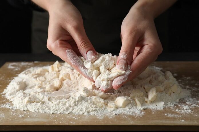 Woman making shortcrust pastry at table