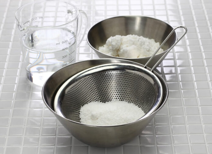 Fine Italian pasta flour being sifted through a metal sieve with water and additional flour prepared for fresh pasta dough