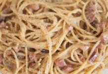 Creamy spaghetti carbonara with bacon pieces and black pepper