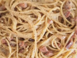 Creamy spaghetti carbonara with bacon pieces and black pepper