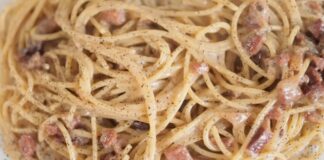 Creamy spaghetti carbonara with bacon pieces and black pepper