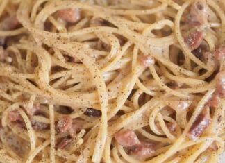Creamy spaghetti carbonara with bacon pieces and black pepper