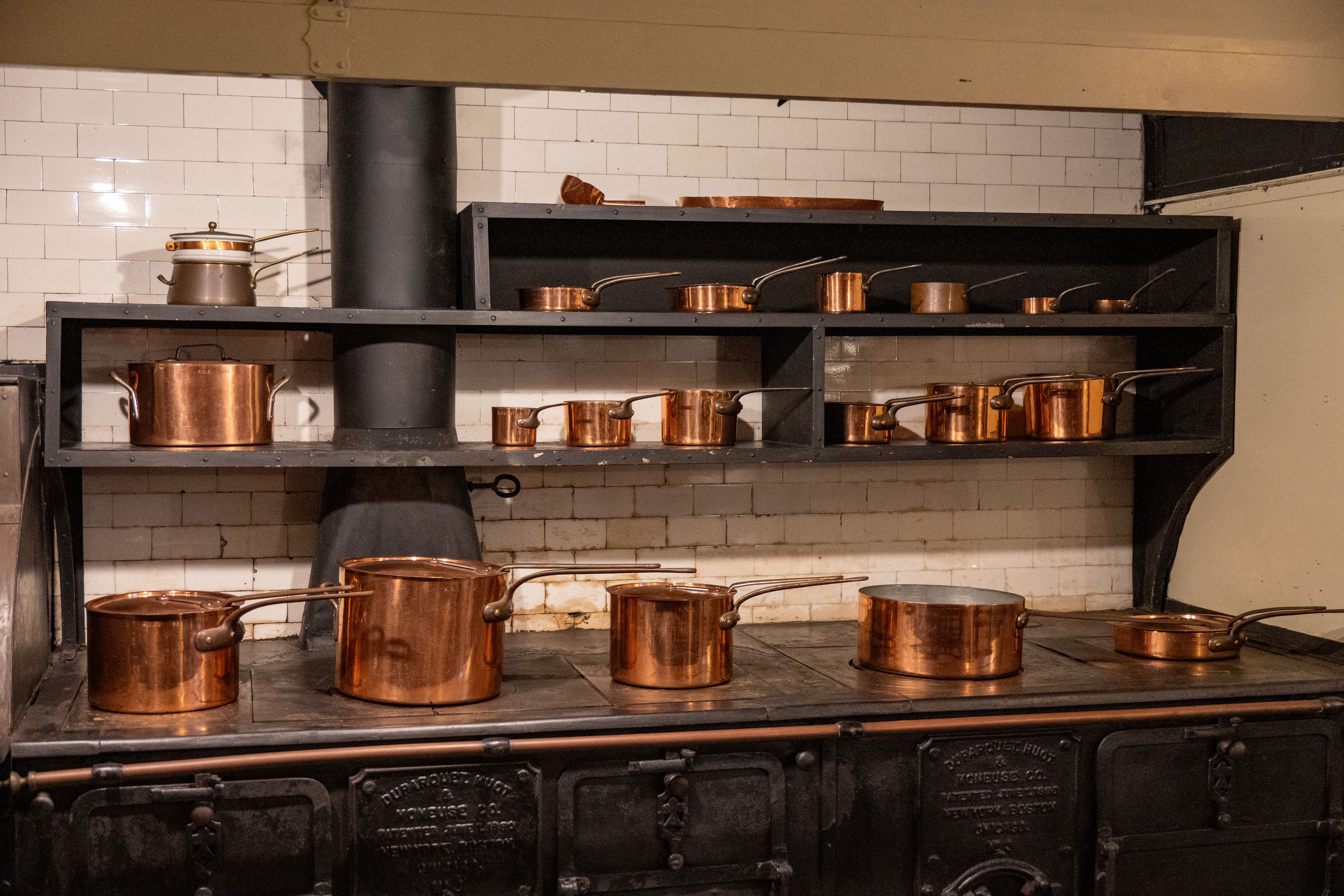 Copper cookware arranged on a kitchen stove, showing a traditional pan material option for making risotto.